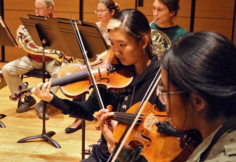 Closeup of music students in violin section of the orchestra